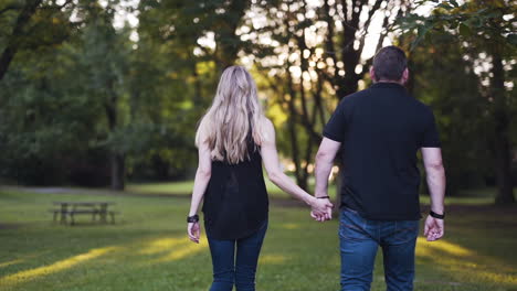 Young-couple-walking-into-the-sunset-in-a-beautiful-park