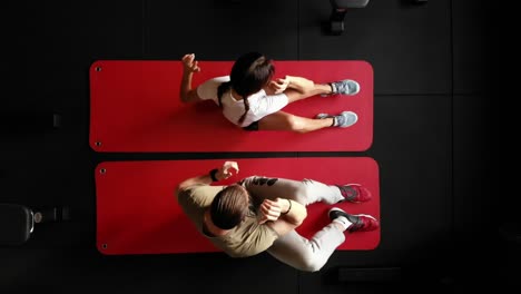 Disparo-De-Arriba-Hacia-Abajo-De-Una-Mujer-Deportiva-Haciendo-Ejercicio-En-El-Gimnasio-En-Una-Alfombra-Con-Entrenador-Personal