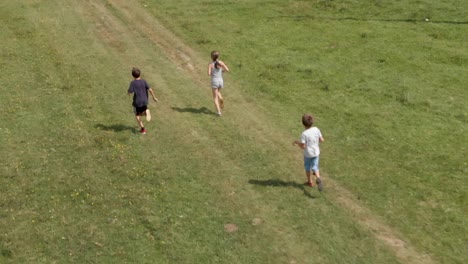 Los-Niños-Corren-Y-Juegan-En-El-Campo-Verde---Cámara-Lenta-Aérea