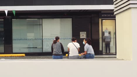 Tres-Damas-Se-Sientan-Afuera-De-Una-Tienda-Cerrada-En-La-Ciudad-De-Panamá-Durante-El-Coronavirus,-2021