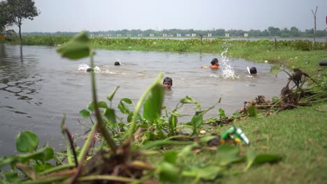 Little-rural-children-enjoying-and-bathing-in-pond-or-river,-splashing-in-water,-slow-motion