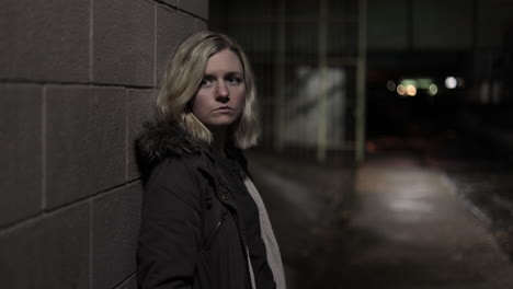 Girl-leans-against-a-wall-in-an-alley-at-night