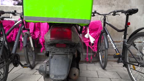 Food-delivery-bikes-and-bags-lined-up-against-wall-in-Urban-environment-SLOW-MOTION