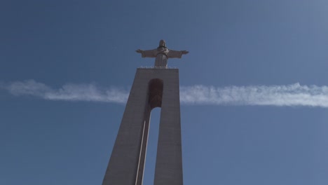 Pan-to-reveal-towering-Christ-the-King-National-Sanctuary-statue-in-Almada,-Portugal