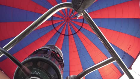 Inflating-hot-air-balloon,-detail-of-flames-and-burner-during-flight,-cinematic-shot