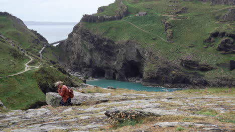 Gente-De-Vacaciones-Caminando-Sobre-Un-Acantilado-A-Lo-Largo-Del-Camino-Que-Conduce-A-Las-Ruinas-Del-Castillo-De-Tintagel-Y-Al-Puente-A-La-Isla-En-Cornualles