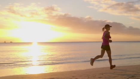 Una-Mujer-Que-Pasa-Frente-Al-Sol-Mientras-Corre-En-La-Playa-Al-Atardecer-En-Una-Hermosa-Isla