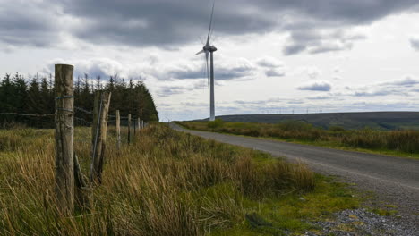 Lapso-De-Tiempo-De-La-Turbina-Del-Parque-Eólico-En-La-Distancia-Con-Los-Coches-Conduciendo-Y-La-Gente-Caminando-Por-La-Carretera-En-Las-Montañas-De-Arigna-En-Irlanda