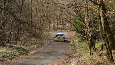 Fahren-Durch-Eine-Leichte-Kurve-Mit-Blick-Auf-Das-Heck-Eines-Rallye-Autos,-Aus-Dem-Steine-Und-Blätter-Fliegen,-Während-Eines-Rennherbsttages-Bei-Einer-Valasska-Rallye,-Aufgenommen-In-Zeitlupe-Mit-120-Fps