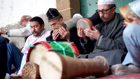 Low-angle-shot-of-gathering-of-men-in-traditional-clothing-chanting-and-hitting-drums-going-into-a-trance-during-a-sufi-ceremony