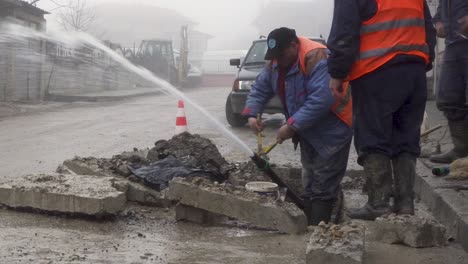 Trabajadores-De-La-Ciudad-Reparando-Una-Tubería-De-Agua-Rota-Con-Agua-Rociada-Por-Toda-La-Calle-En-Bulgaria