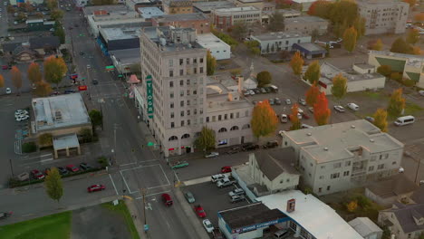 City-of-Coos-Bay-in-autumn,-red-trees,-and-highway-101-running-through-town,-drone-reveal