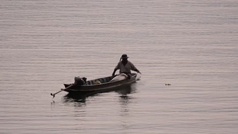 Fisherman-silhouetting-as-he-is-casting-and-drawing-his-net-in-the-River-before-dark,-in-slow-motion