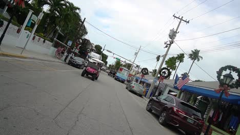 Tiro-De-ángulo-Holandés-De-La-Calle-Key-West-Con-Lámparas-De-Streep-Decoradas-Con-Coronas-De-Navidad-Con-Carrito-De-Golf-Conduciendo-Hacia-La-Cámara