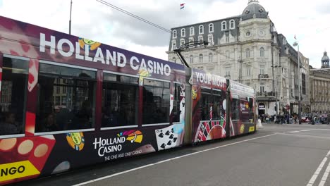 Tram-on-roadway-in-Amsterdam,-Netherlands,-Holland-showing-advertisements-along-the-entire-length-of-the-vehicle-and-an-efficient-public-transport-system-in-the-City