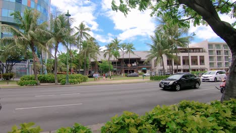 Coches-Que-Pasan-Por-La-Carretera-De-Tráfico-Con-Hoteles-De-Lujo-Y-Palmeras-En-La-Parte-Trasera-En-Un-Día-Soleado-En-Hawaii