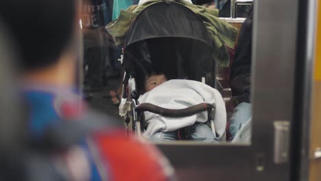 Un-Lindo-Bebé-Japonés-En-Un-Cochecito-Que-Viaja-En-Un-Tren-En-Tokio,-Japón---Cierra-A-Cámara-Lenta