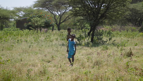 Two-local-kids-pose-smiling-for-camera-outdoors-in-Ziway,-Ethiopia