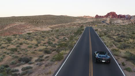 Black-Ferrari-convertible-sports-car-driving-through-the-Valley-of-Fire-at-sunset