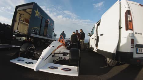 Crew-Making-Final-Adjustments-To-Parked-Race-Car-In-Malta---wide-shot