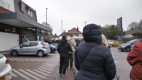 Die-Menschen-Stehen-Vor-Der-Supermarktkette-Aldi-An,-Bevor-Sie-Morgens-Geöffnet-Ist,-Um-Während-Der-Koronaviruskrise-Und-In-Vorbereitung-Auf-Die-Quarantäne-In-Großbritannien-Einzukaufen-Und-Sich-Mit-Lebensmitteln-Einzudecken