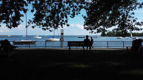 Wide-shot-of-a-man-sitting-on-a-bench-enjoying-the-lake-view