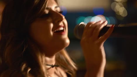 Schöne-Kaukasische-Frau,-Die-Das-Singen-Auf-Der-Bühne-Mit-Bokeh-lichtern-Im-Hintergrund-Genießt