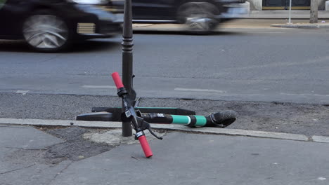 Scooters-Eléctricos-Tirados-En-La-Acera-En-Las-Calles-De-París-Cerca-De-Los-Campos-Elíseos