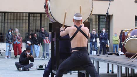 Hombre-Con-Diadema-Tocando-El-Tambor-Vertical-De-La-Tradición-Musical-Japonesa-Durante-Un-Evento-Público-Al-Aire-Libre