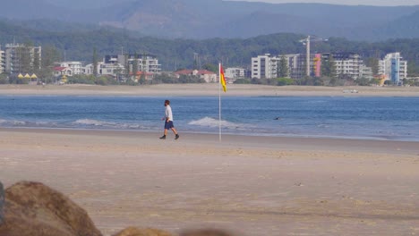 Mann,-Der-Den-Strand-Verlässt,-Nachdem-Er-Die-Flagge-Des-Rettungsschwimmers-Bei-Snapper-Rocks-Gesetzt-Hat---Meereswellen-In-Rainbow-Bay---Coolangatta,-Gold-Coast,-Queensland,-Australien