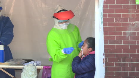 female-doctor-wearing-full-anticovid-suit-while-conducting-a-covid-test-on-a-patient