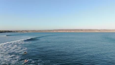 Aerial-view-moving-forward-shot,-Surfer-on-the-beach-catching-some-waves-on-a-bright-sunny-day-in-San-Juanico,-California-Sur,-Mexico,-sandy-land-and-blue-sea-in-the-background