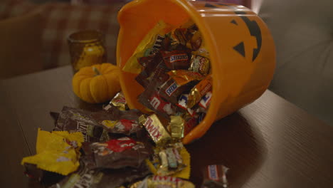 Cerrar-La-Inclinación-De-Un-Caramelo-De-Halloween-Derramándose-De-Un-Cubo-De-Calabaza