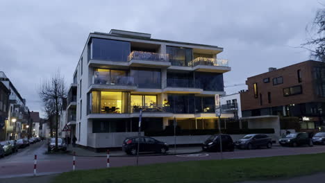 Edificio-Residencial-Moderno-De-Lujo-Con-Luces-En-La-Ventana-Durante-El-Cielo-Nublado-En-Segundo-Plano