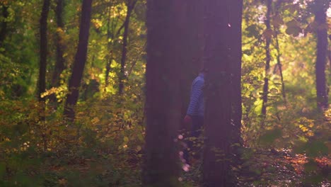 Couple-Walking-Into-The-Forest-Passing-Through-Trees-In-Sunny-Autumn-Morning,-Tracking-Shot,-Slow-Motion