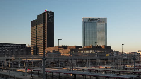 Postgirobygget-And-Radisson-Blu-Plaza-Hotel-In-Oslo,-Norway-With-Oslo-Central-Station-In-Foreground-At-Dusk---View-From-The-Barcode-Project---timelapse