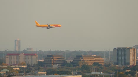 Toma-De-Seguimiento-Del-Avión-De-Dhl-Que-Vuela-Sobre-El-Paisaje-Urbano-De-Toronto-Con-Tráfico-En-La-Autopista