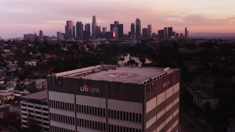 Toma-Aérea-Sobrevolando-El-Edificio-Para-Revelar-El-Centro-De-Los-Ángeles-Durante-La-Puesta-De-Sol