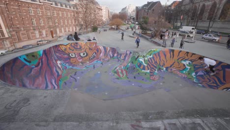 Young-man-rides-a-scooter-in-the-skate-park-pool,-enjoys-riding-fast-and-maintains-balance