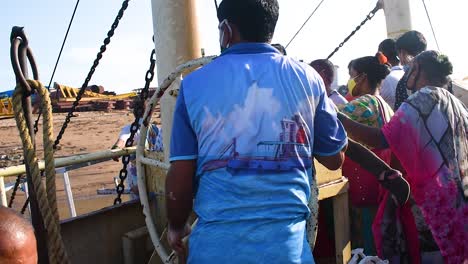 A-worker-in-ferryboat-rotating-a-big-wheel-of-a-winch-of-the-boat-and-trying,-An-Indian-worker-or-sailor-closing-the-winch-of-the-boat-with-a-big-wheel-in-boat-full-of-passengers-and-travelers