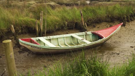 4k-Altes-Holzfischerboot,-Das-An-Den-Schlammigen-Ufern-Eines-Flusses-Bei-Ebbe-Seltsam-Ist