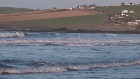 Coastal-village-in-the-distance-with-morning-tidal-waves-rushing-to-shore