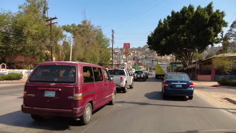 Fahren-Auf-Einer-Belebten-Straße-In-Tijuana,-Mexiko-An-Einem-Sonnigen-Tag-Mit-Geschäftsbetrieben-Daneben