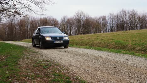 Person-driving-old-VW-Bora-near-a-forest-on-a-rural-road