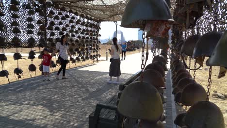 Azerbaijani-pose-for-photographs-in-front-of-a-display-of-dead-Armenian-soldiers-helmets-in-Trophy-park,-Baku,-Azerbaijan