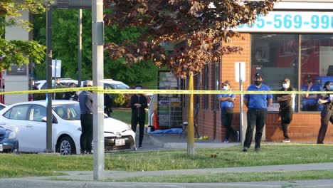 Yellow-taped-area-with-building-and-police-officers,-crime-scene