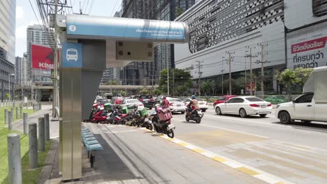 City-bus-stop-with-busy-traffic-on-road-in-midtown-of-modern-town-in-Bangkok,-Thailand