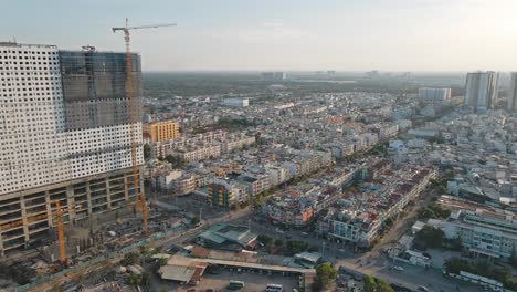 Drone-flying-fordwards-shows-a-building-under-construction-with-clear-sky-line-and-residential-area