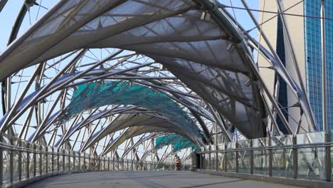 Gente-Trotando-Y-Montando-En-Bicicleta-Temprano-En-La-Mañana-En-El-Puente-Helix,-Marina-Bay,-Singapur