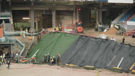 Trabajadores-Manuales-En-Ropa-De-Trabajo-Protectora-Trabajando-En-La-Construcción-De-Un-Estadio-De-Fútbol-En-Madrid,-España